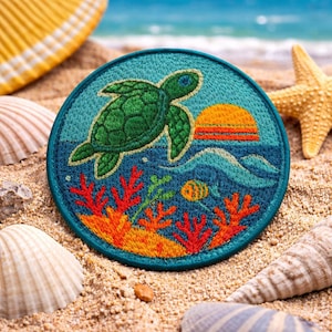 以下が含まれることがあります： 緑色のウミガメがサンゴと夕日の上を泳いでいる刺繍パッチ。丸いパッチはターコイズブルーの背景で、砂浜の表面に貝殻とヒトデに囲まれています。