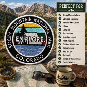 May include: A circular embroidered patch featuring a landscape of mountains, trees, and a cabin with the text "ROCKY MOUNTAIN NATIONAL PARK", "EXPLORE.", and "COLORADO". The patch is displayed alongside a compass, sunglasses, and a mug.