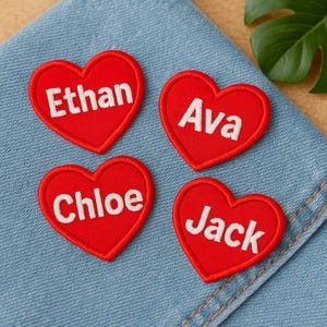 May include: Four red heart-shaped embroidered patches with white text. The names "Ethan", "Ava", "Chloe", and "Jack" are displayed on each patch. The patches are on a blue denim surface.