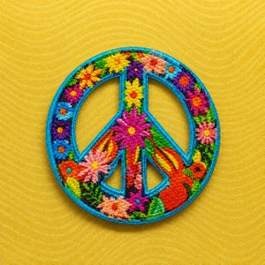May include: A circular embroidered patch featuring a peace sign symbol. The design is composed of various colorful flowers in shades of pink, yellow, orange, purple, and blue, all outlined with a bright blue border against a dark background.