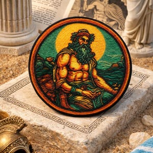 May include: A circular embroidered patch depicting a seated figure with a long beard, laurel wreath, and robes. The design features a yellow sun, green background, and orange border. The patch is displayed on a stone surface.