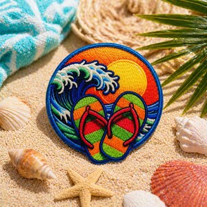May include: Embroidered patch featuring a beach scene with a setting sun, ocean waves, and a pair of colorful flip-flops. The patch is round with a blue border. Seashells, a starfish, and a towel are in the background.