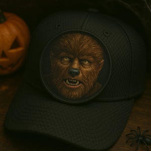 May include: Black baseball cap featuring a detailed, circular patch with a werewolf illustration. The werewolf has brown fur, yellow eyes, and visible fangs. The cap has a textured pattern and a curved brim, perfect for Halloween.