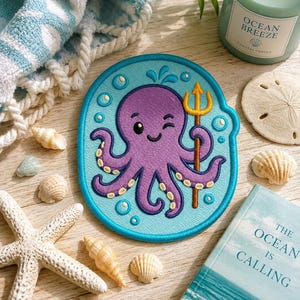 May include: A circular embroidered patch featuring a purple octopus with a winking expression, holding a golden trident. The octopus is surrounded by light blue water bubbles and a dark blue border, set against a light blue background.