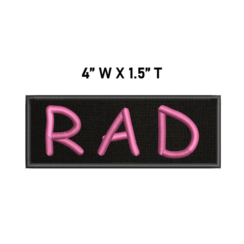 May include: A rectangular black embroidered patch featuring the pink stitched text RAD. The patch has a black border and measures 10.16 cm wide by 3.81 cm tall as indicated by the text above the item.