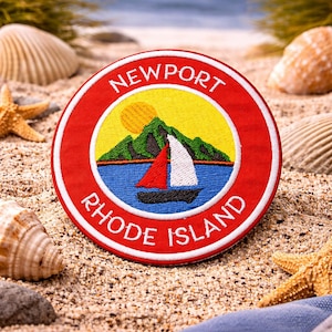 May include: Embroidered patch with a red border and the words "Newport Rhode Island". The patch features a sailboat on blue water, a yellow sun, and green mountains. The patch is surrounded by seashells and sand.
