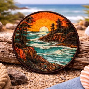 May include: Round embroidered patch featuring a sunset over a coastal landscape. The design includes a vibrant orange and yellow sky, turquoise water, and dark green trees. The patch is framed with a brown border and set on a sandy surface.