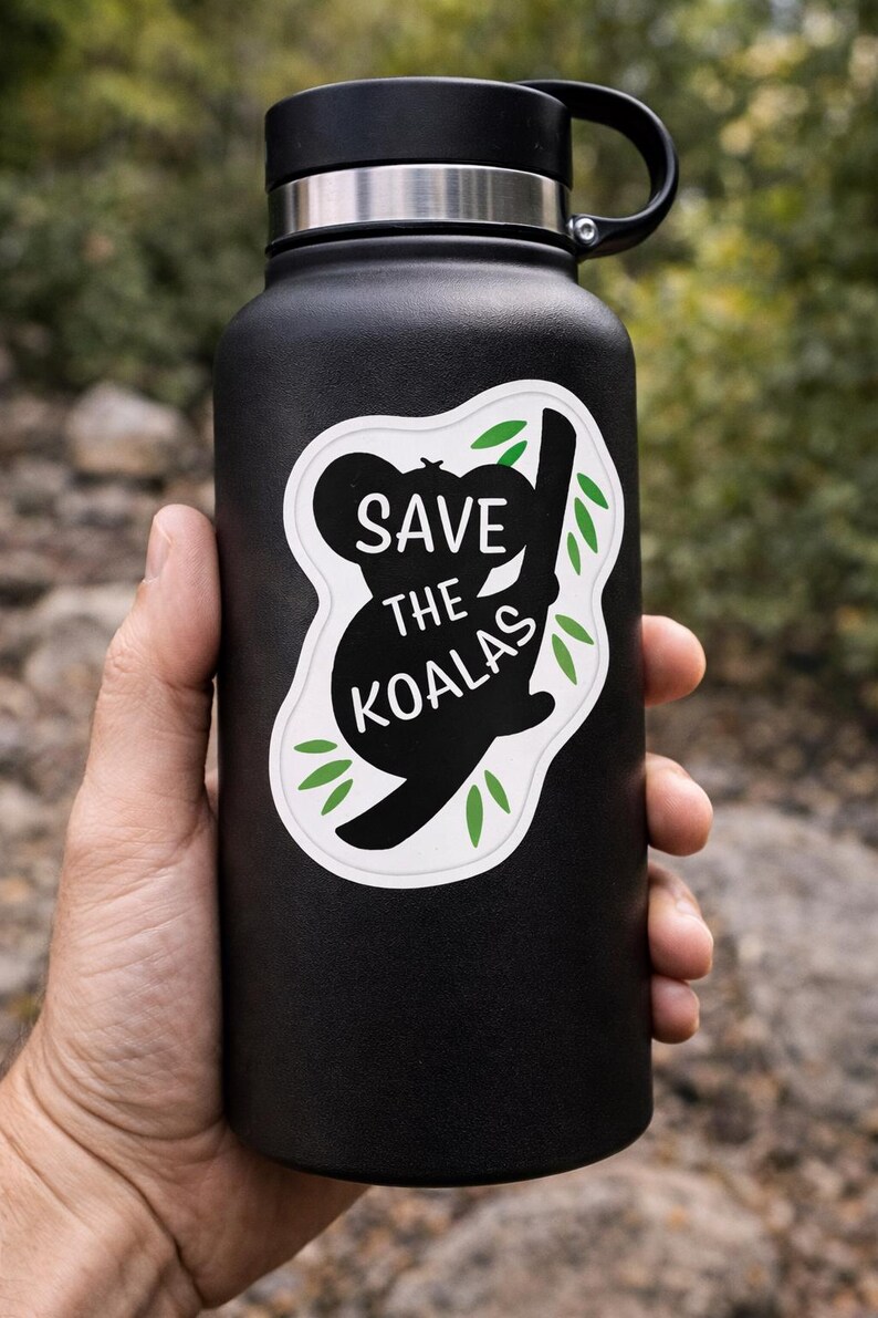 May include: Black insulated water bottle with a black lid and handle. A white sticker on the bottle features a black koala bear silhouette with the words "SAVE THE KOALAS" in white and green leaves.