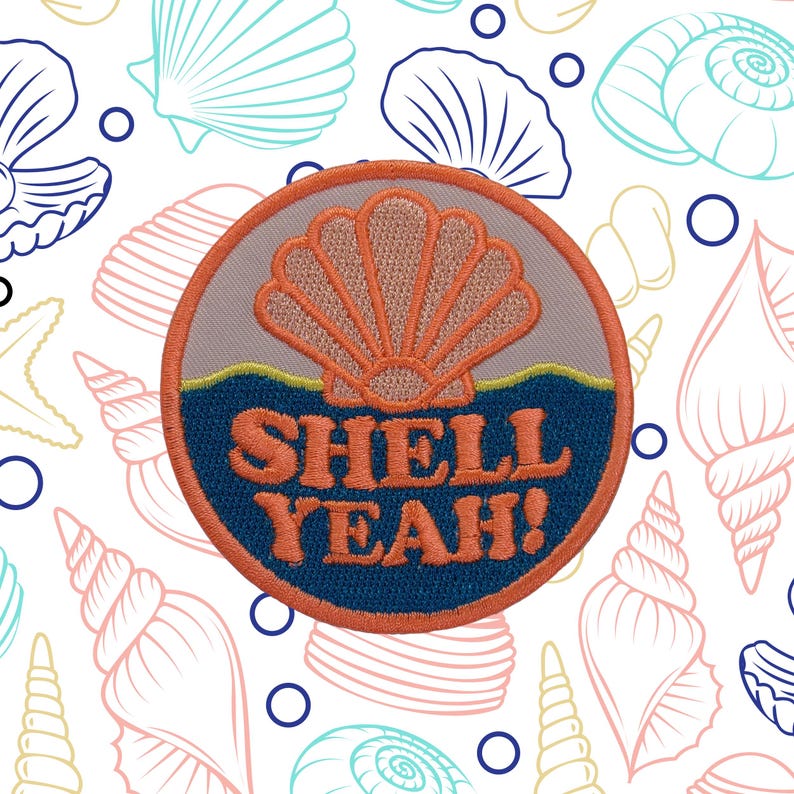 Peut inclure: &Eacute;cusson brod&eacute; avec un motif de coquillage et les mots "SHELL YEAH!" en orange. L'&eacute;cusson a un fond gris avec une bordure orange et un motif de vagues bleues. Le fond est blanc avec des illustrations de coquillages.