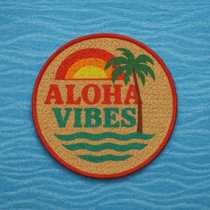 Könnte beinhalten: Runder Aufnäher mit rotem Rand und den Worten "ALOHA VIBES" in Rot und Türkis. Das Design zeigt einen Sonnenuntergang, eine Palme und Meereswellen. Auf einem strukturierten blauen Stoffhintergrund.