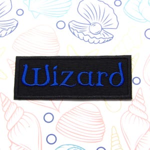 Peut inclure: &Eacute;cusson brod&eacute; noir avec le mot "Wizard" en lettres bleues.