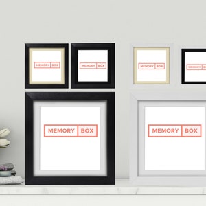 May include: Five black and white picture frames with the text "MEMORY BOX" in red on a white background. The frames are arranged in a grid pattern on a white wall.
