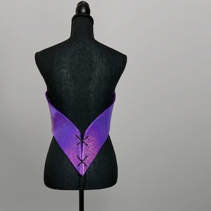 May include: Purple iridescent corset with black lacing at the back. The corset is on a black dress form.