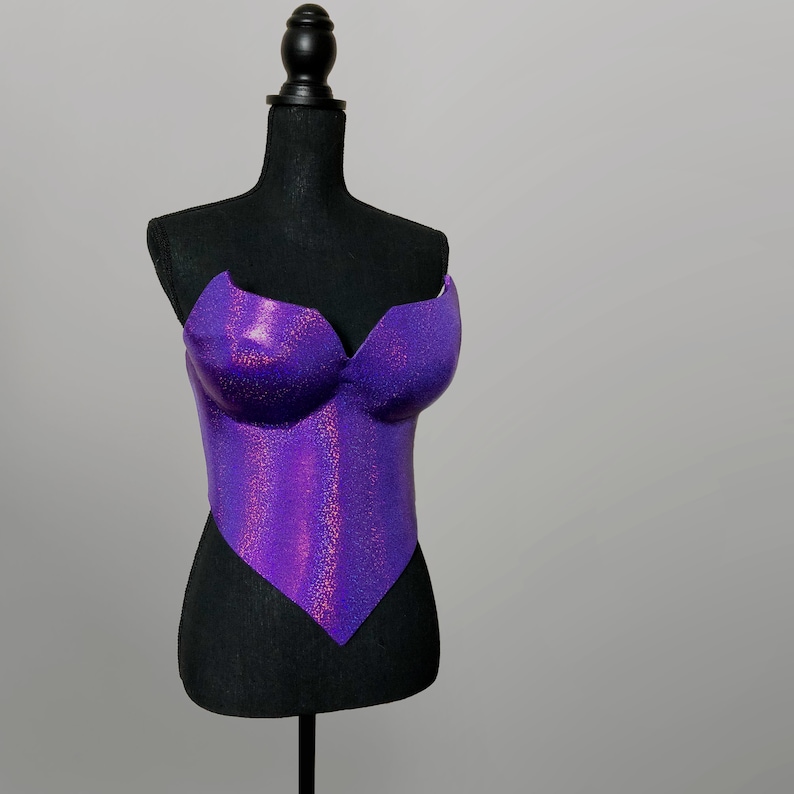 May include: A purple glitter corset with a sweetheart neckline. The corset is on a black dress form.
