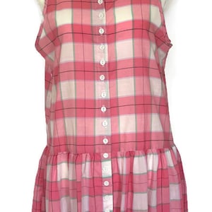May include: A pink and white plaid sleeveless dress with a button-up front. The dress has a gathered skirt and a relaxed fit.