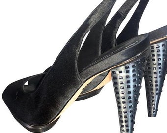 May include: Black slingback heels with a peep-toe design. The heels have a unique, cone-shaped design with a silver, perforated metal finish. The shoes have a satin-like texture and a platform sole.