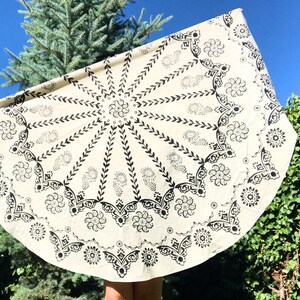 Decorative border with scalloped edges and Ottoman-inspired ornamental details. Natural cotton fabric with crisp black block printing on a cream background. Styled-in outdoor garden setting with small potted plants and decorative elements.