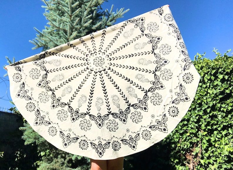 Decorative border with scalloped edges and Ottoman-inspired ornamental details. Natural cotton fabric with crisp black block printing on a cream background. Styled-in outdoor garden setting with small potted plants and decorative elements.