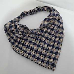 Puede incluir: Una diadema de cuadros azules y beige con una banda elástica.