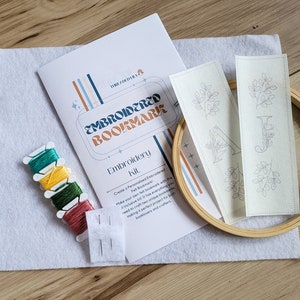 May include: Embroidered bookmark kit with two pre-printed designs, embroidery floss, needles, and a wooden embroidery hoop. The kit includes instructions for creating personalized bookmarks.