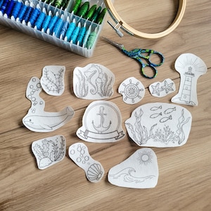 May include: A set of 11 embroidery patterns featuring nautical themes. The patterns include a whale, anchor, lighthouse, seashells, starfish, and seaweed. The patterns are printed on white paper and are ready to be stitched.