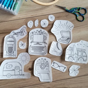 May include: A set of 10 black and white embroidery patterns on white paper. The patterns include a vintage jukebox, a typewriter, a record player, a camper, a camera, roller skates, a van with a surfboard, and three starburst designs.