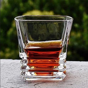 May include: A clear glass whiskey tumbler with a layered, geometric design. The glass is filled with amber-colored liquid.