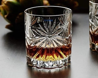 May include: Two clear glass tumblers with a cut-glass design. The glasses are filled with a dark amber liquid.
