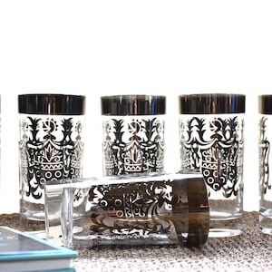 May include: Set of six vintage highball glasses with a black and white geometric design. The glasses have a silver rim and are perfect for serving cocktails or water.