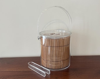 May include: A clear acrylic ice bucket with a bamboo liner and a handle. The bucket is sitting on a wooden surface.