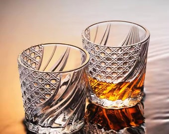 May include: Two clear glass tumblers with a swirling, textured design. The larger tumbler is filled with a golden amber liquid.