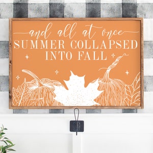 May include: A wooden sign with an orange background and white text and illustrations. The sign reads "and all at once SUMMER COLLAPSED INTO FALL" with a stylized image of pumpkins and leaves.