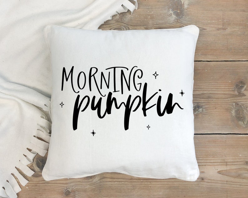 May include: White throw pillow with black text that reads "Morning Pumpkin" and small star accents.