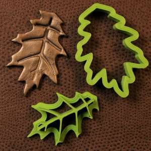 May include: Three leaf-shaped cookie cutters, two green and one brown. The green cutters are detailed with a raised vein pattern. The brown cutter is a solid leaf shape.