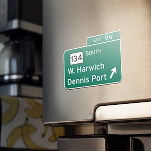 May include: Green highway sign with white text. The sign reads "Exit 9A", "South", "134", "W. Harwich", and "Dennis Port". An arrow points to the right.