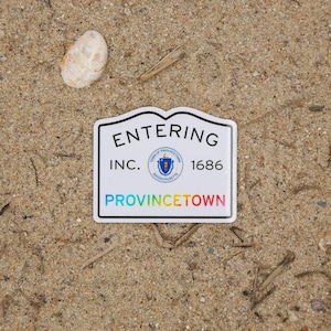 May include: A white rectangular sticker with a black border, featuring the words "ENTERING" and "PROVINCETOWN" in bold text. The sticker also includes the text "INC. 1686" and a town seal. The word "PROVINCETOWN" is in rainbow colors.