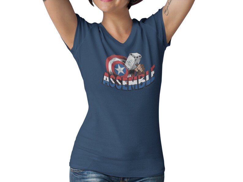 Puede incluir: Una camiseta azul marino de cuello en V con un gr&aacute;fico del escudo del Capit&aacute;n Am&eacute;rica y el martillo de Thor con el texto "ASSEMBLE".