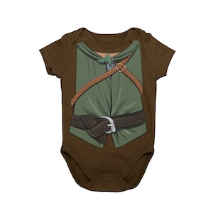 May include: A brown baby onesie with a green and brown illustration of a character wearing a tunic, belt, and a leaf on their chest.