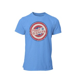 May include: A light blue t-shirt with a distressed red, white, and blue circle graphic featuring a star and the text "FIRST AVENGER".