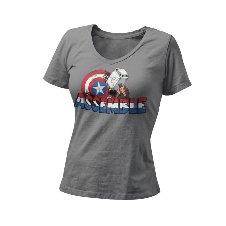 Puede incluir: Camiseta gris de cuello en V con un gr&aacute;fico del escudo del Capit&aacute;n Am&eacute;rica y el martillo de Thor con el texto "ASSEMBLE" debajo.