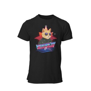 Op de afbeelding: Zwart T-shirt met een retro-grafische afbeelding van een kat met een zonnebril en een leren jack. De afbeelding bevat een ster, neonlichten en het woord "Goose".