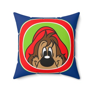Pode incluir: Travesseiro azul com um círculo vermelho, branco e verde com um personagem de desenho animado com pelo marrom, um chapéu vermelho e olhos grandes.