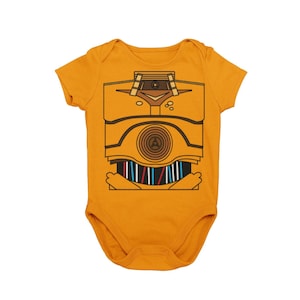 May include: A yellow baby onesie with a graphic of a robot's torso. The robot is brown and has a circular design on its chest.