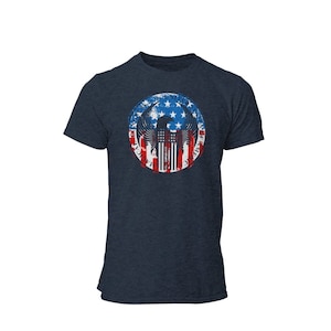 May include: A navy blue t-shirt with a distressed circle graphic featuring an eagle with outstretched wings, a red, white, and blue American flag, and the text "United We Stand, Divided We Fall".