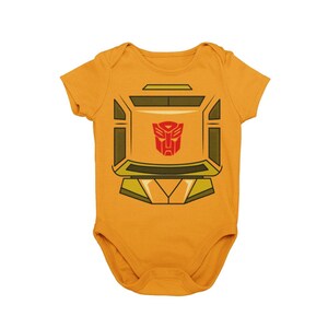 May include: A yellow baby onesie with a graphic of a robot face with a red Autobot symbol on the chest.