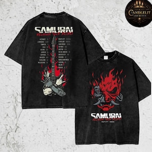 May include: Black, acid-wash t-shirts featuring the text "SAMURAI REUNION TOUR 2020" with a graphic of a guitar and a list of tour cities on the back. The front of the shirt displays a red oni mask design.