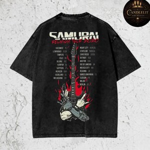 May include: Black t-shirt featuring the text "SAMURAI REUNION TOUR 2020" with a graphic of a guitar engulfed in flames. The shirt lists tour locations including Detroit, Boston, and San Diego.