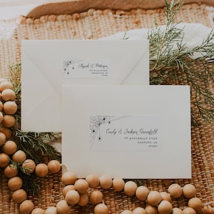 May include: Two white envelopes with black spiderweb and spider designs. The top envelope has the text "Shyrah & Patterson 220 Main Street,  Fernville, OR 97260". The bottom envelope has the text "Emily & Jackson Greenfield 67 Maplewood Lane, Ashford, OR 97260".
