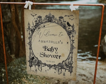May include: A vintage-style sign with a black and white illustration of a spooky, ornate frame with bats, spiders, and a raven. The sign reads "Welcome to Annabelle's Baby Shower 10.30.24".