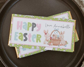 May include: A green and white chocolate bar wrapper with a pink border. It features a Happy Easter message in colorful letters, two bunnies holding a basket of Easter eggs, and the text "Love Annabelle".